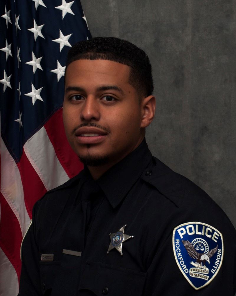 Picture of adult male police officer in front of flag